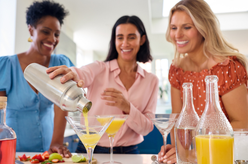 Three mature female friends are at home mixing mocktails together.