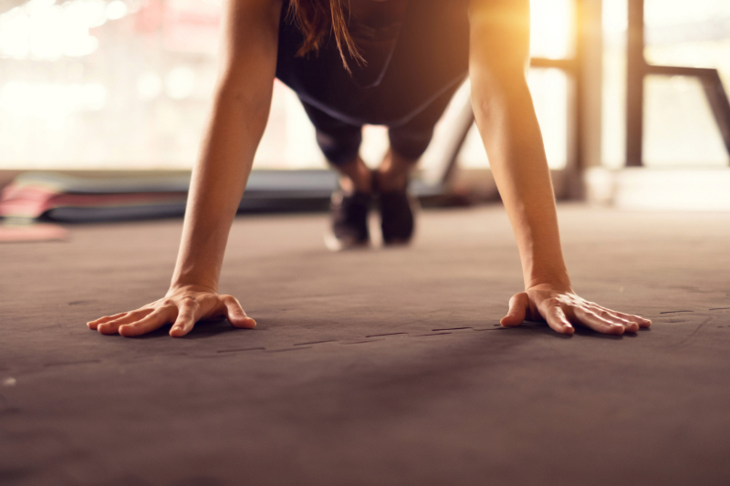 A close-up of a woman in plank position in the gym. 