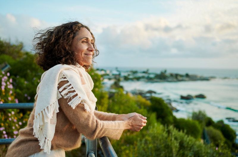 Smiling mature woman wearing a pashmina leaning on a railing.