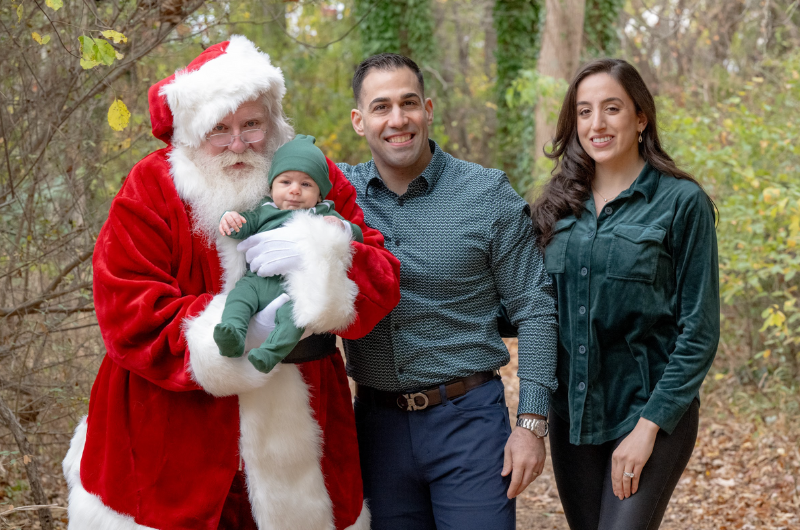 Ron Fierro stands next to his wife and Santa Claus, who is holding a baby.