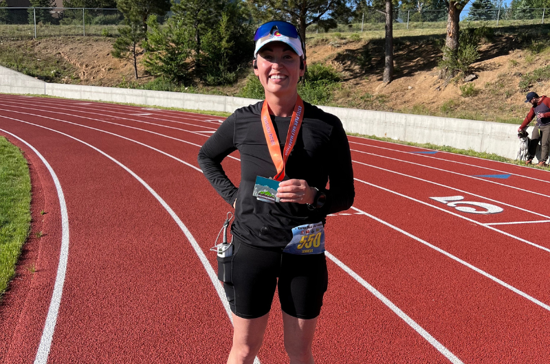 Brunette woman Jennifer Lucero smiles at the camera after running a half marathon.