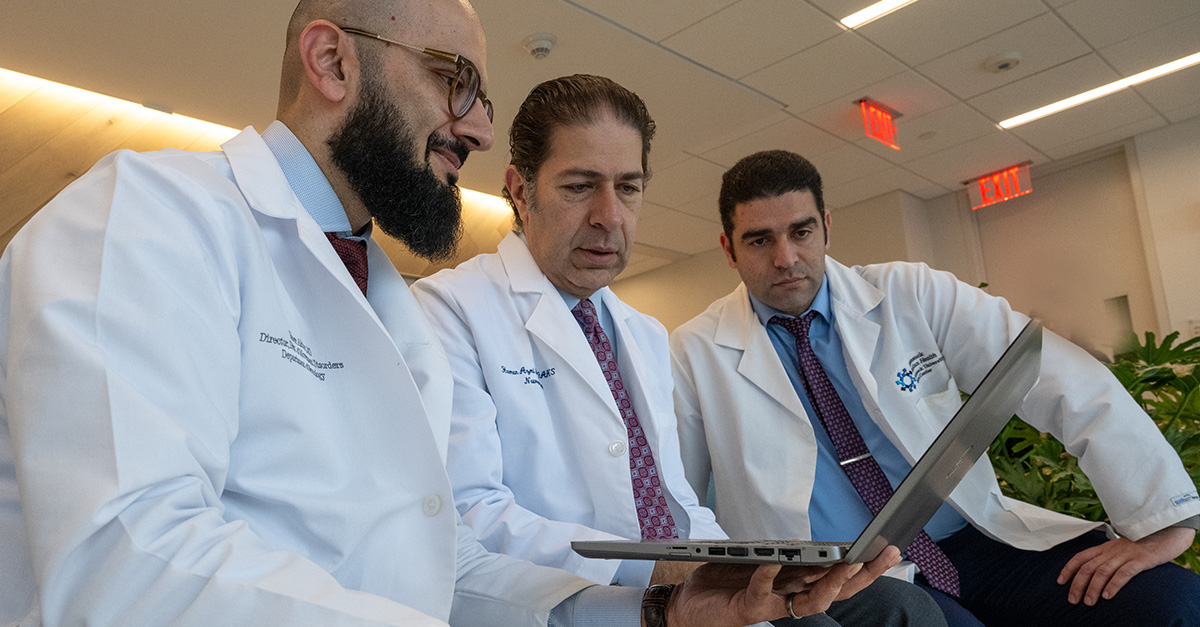 Three doctors reviewing computer screen