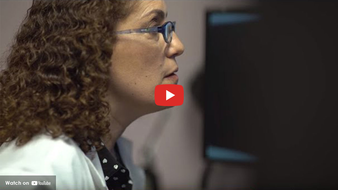 Healthcare professional in a white coat looking at a computer screen.