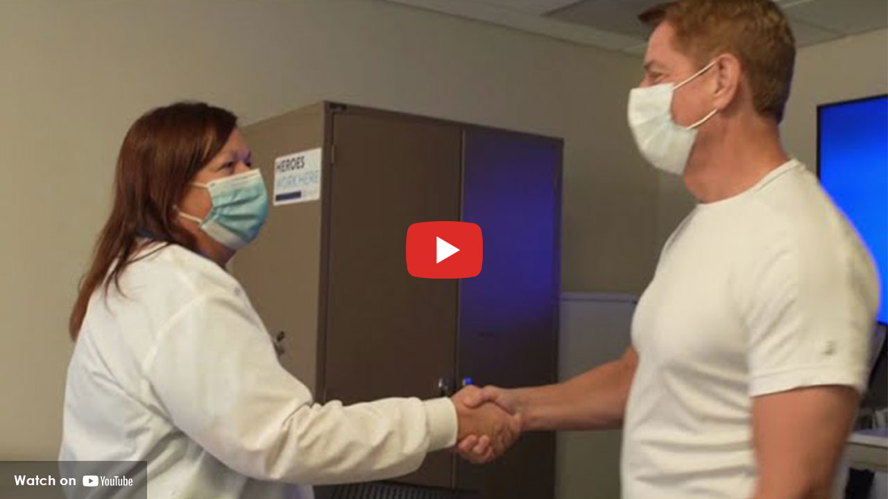 Healthcare professional and patient wearing masks shaking hands in a clinical setting