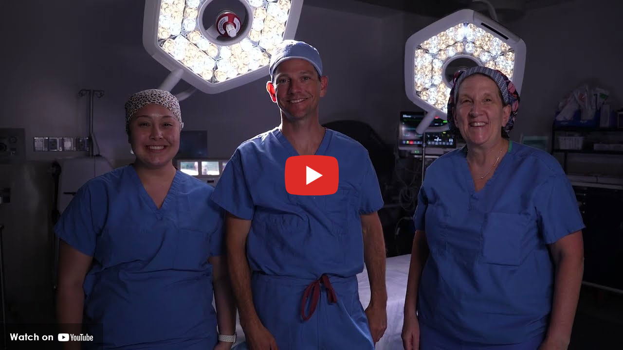 Three surgical team members standing together in an operating room wearing scrubs