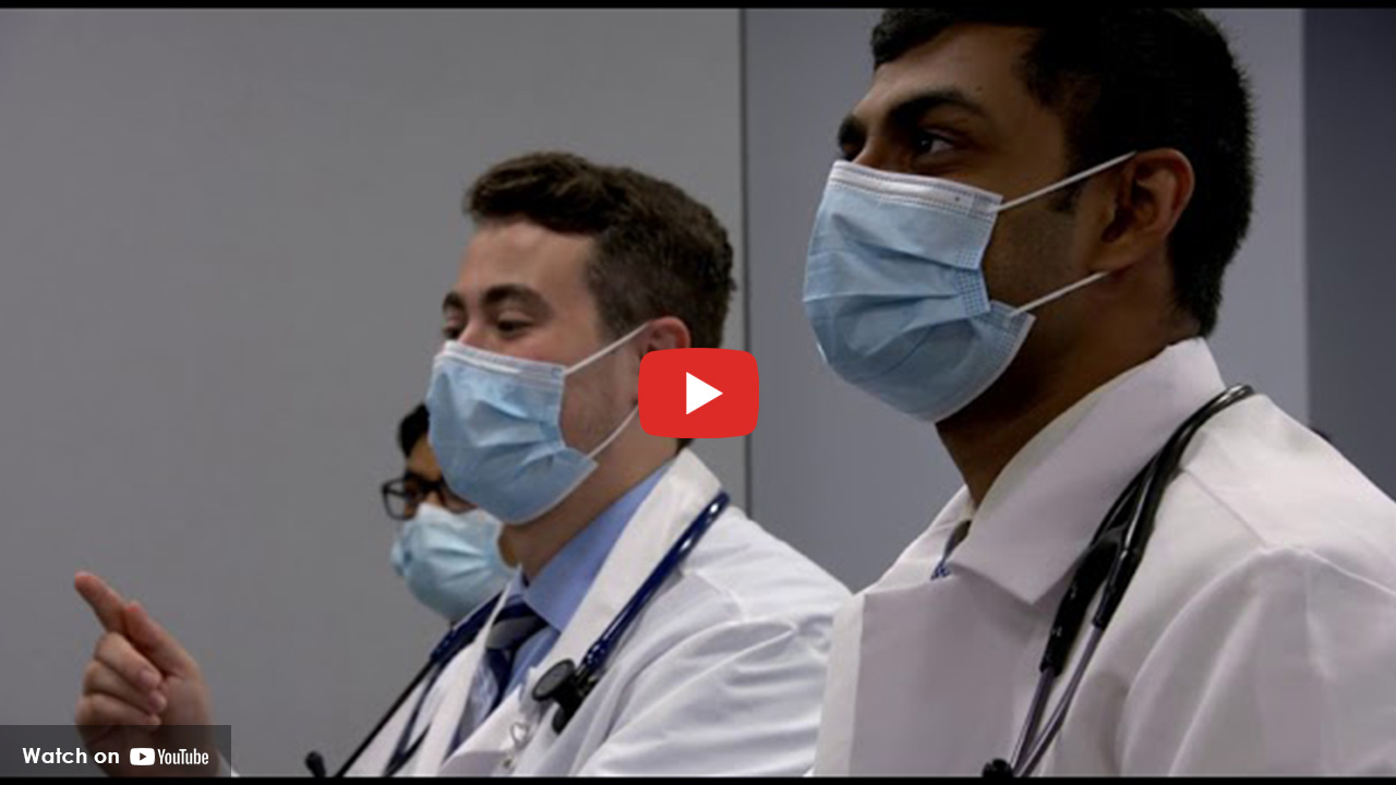 three doctors wearing a facemask in a classroom setting