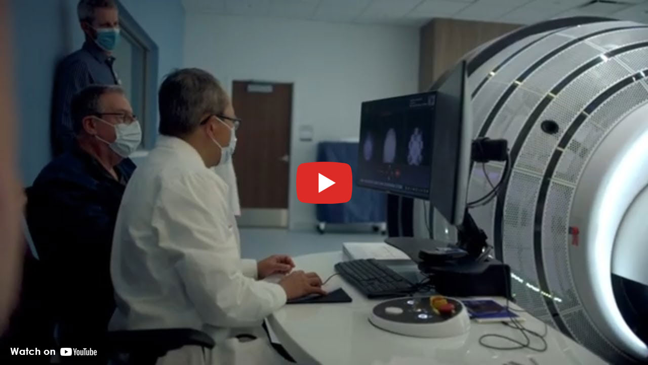 Medical team reviewing brain imaging on a computer next to advanced scanning equipment